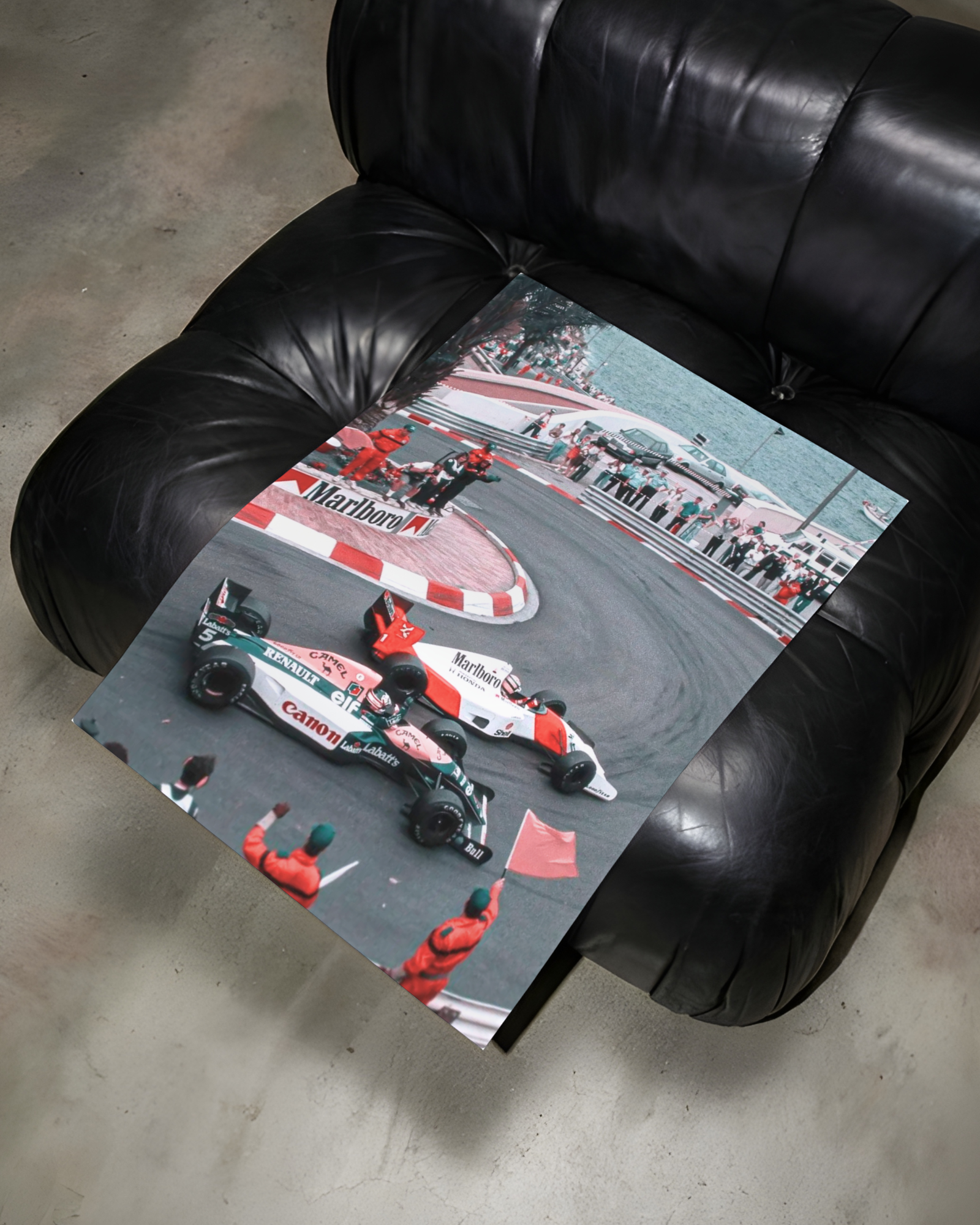 Unframed print of the vintage race-car photo lying across a black leather armchair.