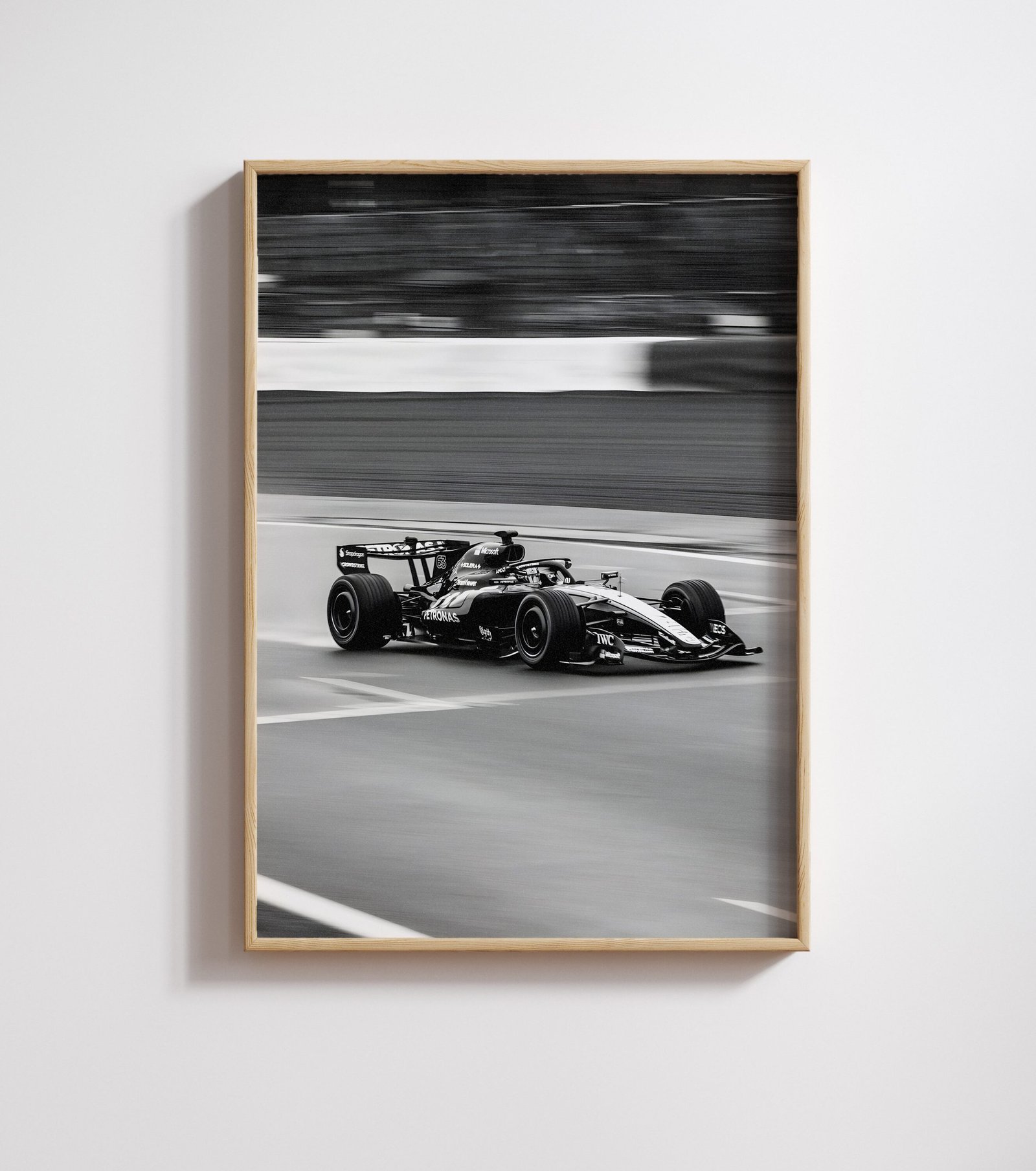 Framed black-and-white photo of a Formula One car cornering on a track, motion-blurred crowd behind.