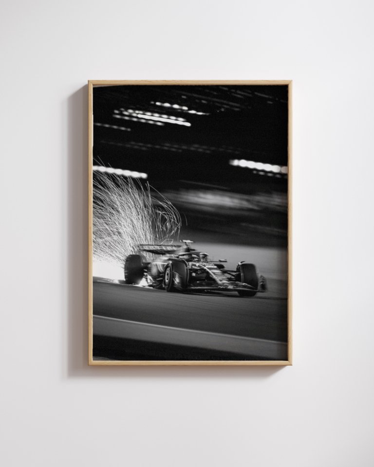 Framed black-and-white print of a Formula One car throwing sparks under blurred night lights.