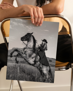 Black and white portrait of a cowgirl riding a horse