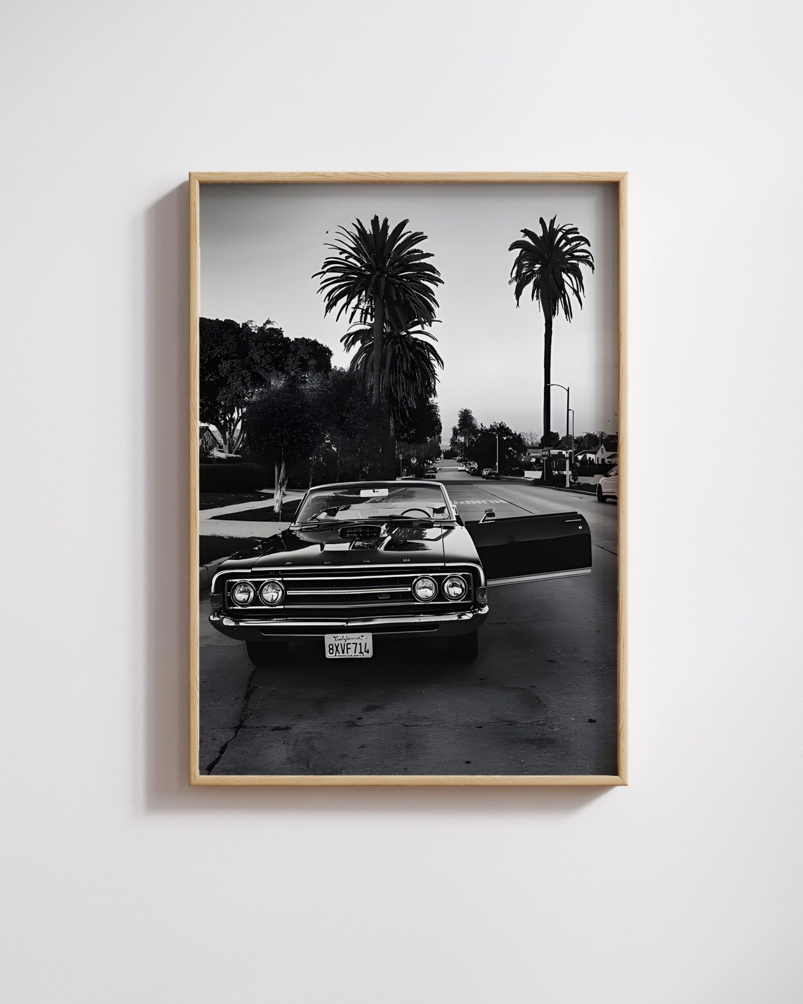 Framed black-and-white photo of a black Chevrolet Impala convertible parked on a palm-lined street.