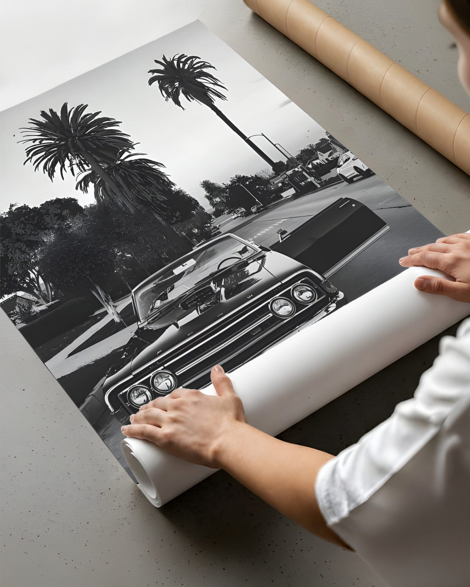 Hands rolling the black-and-white Impala street photo into a paper tube.