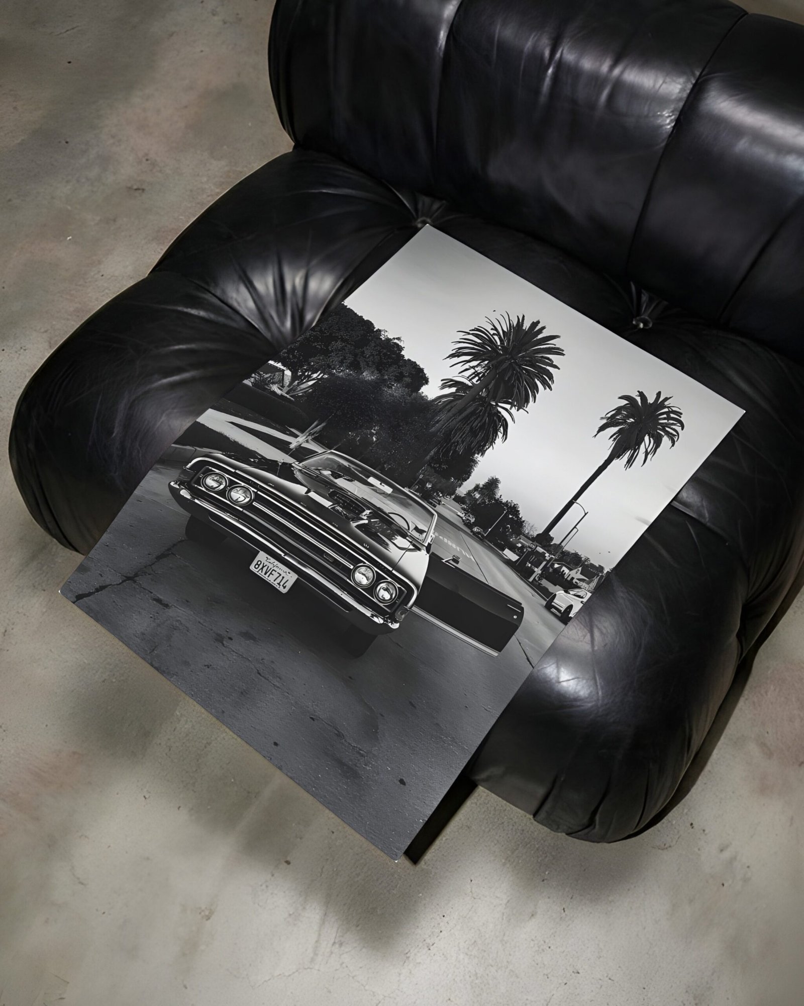 Unframed black-and-white Impala convertible print lying across a black leather armchair.