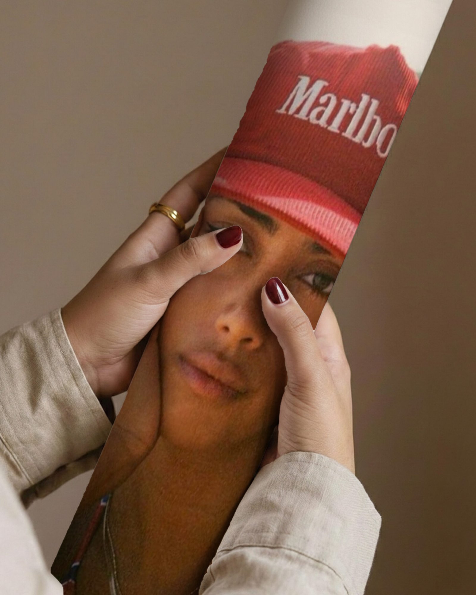 Close-up of hands holding a rolled print showing a red branded cap and a woman's face.
