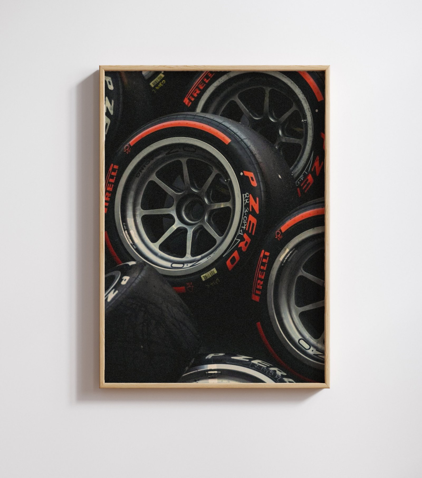 Framed close-up photo of stacked black racing tires with red tread markings and printed branding.