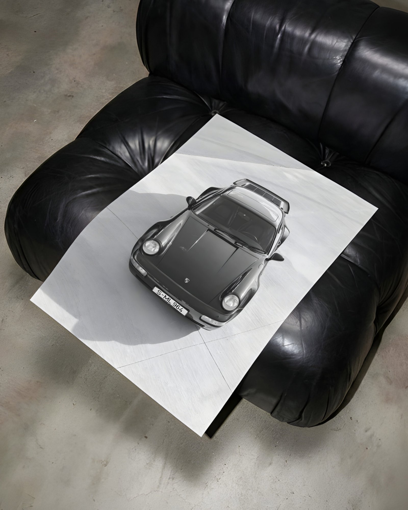 Black-and-white Porsche print laid across a tufted black leather chair.