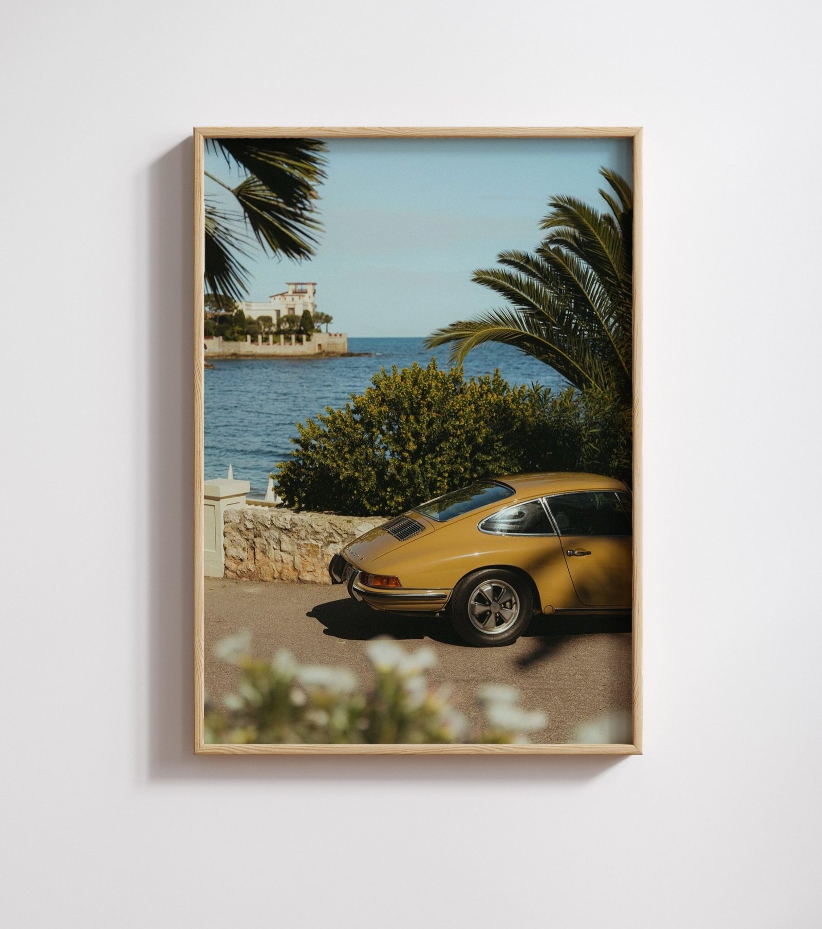 Framed colour photo of a gold vintage Porsche 911 parked beside a coastal road.