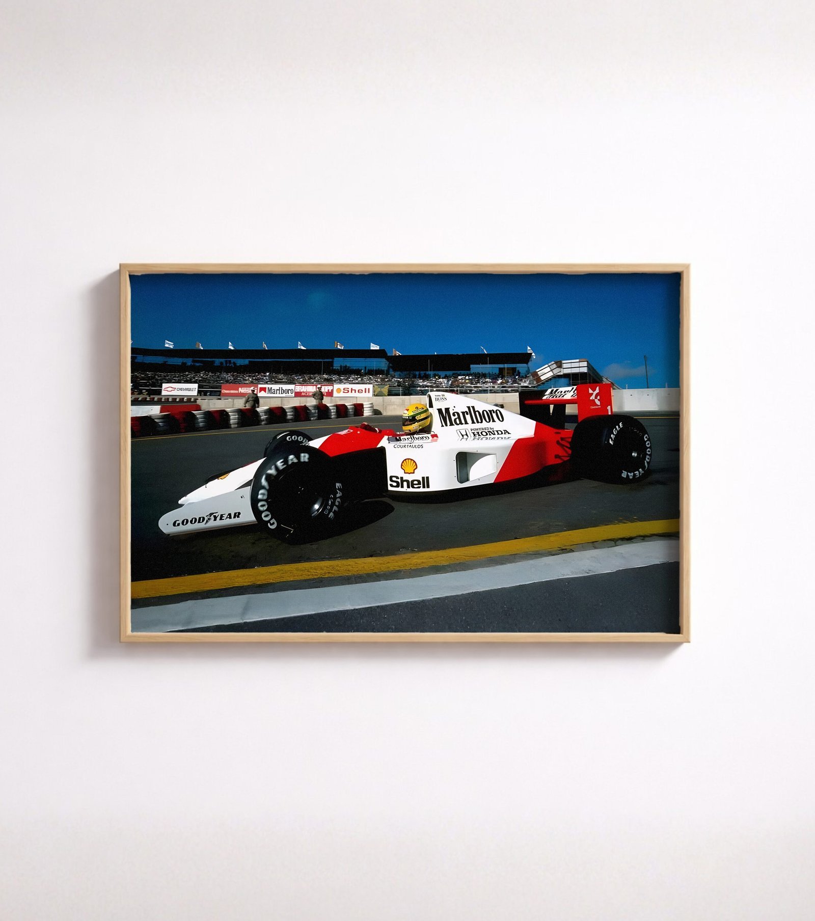 Framed full-colour photo of a red-and-white Formula One car exiting a pit lane.