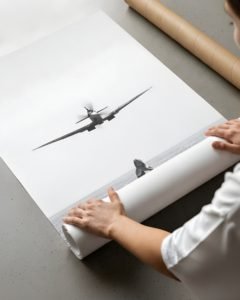 Woman sitting on a dock with a vintage Spitfire flying overhead, cinematic fine art photography.